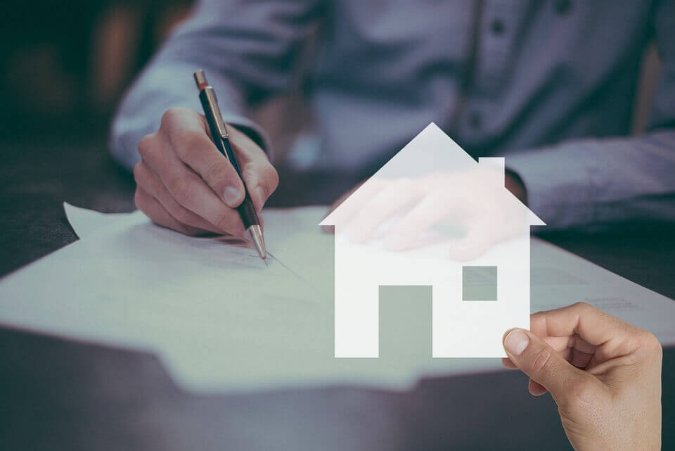 person signing contract with house image overlay
