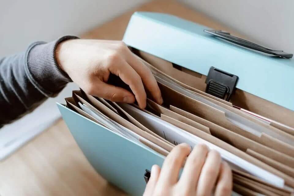 person looking for financial documents in file folder