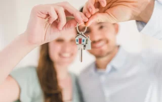 couple proudly holding up key to new home