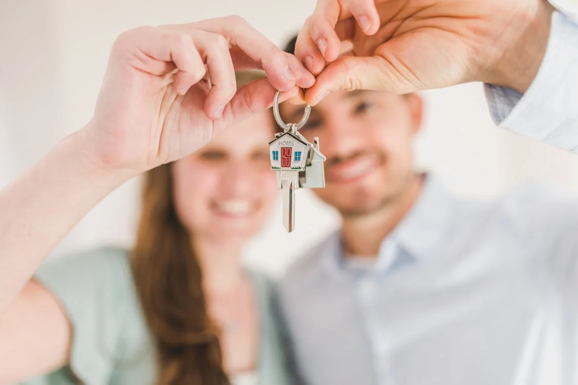 couple proudly holding up key to new home