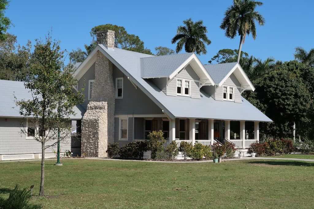 A grey house with a stone chimney on a clear day