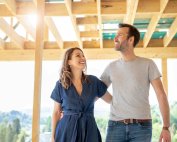 A man and woman walking together through the wooden frame of a newly built house